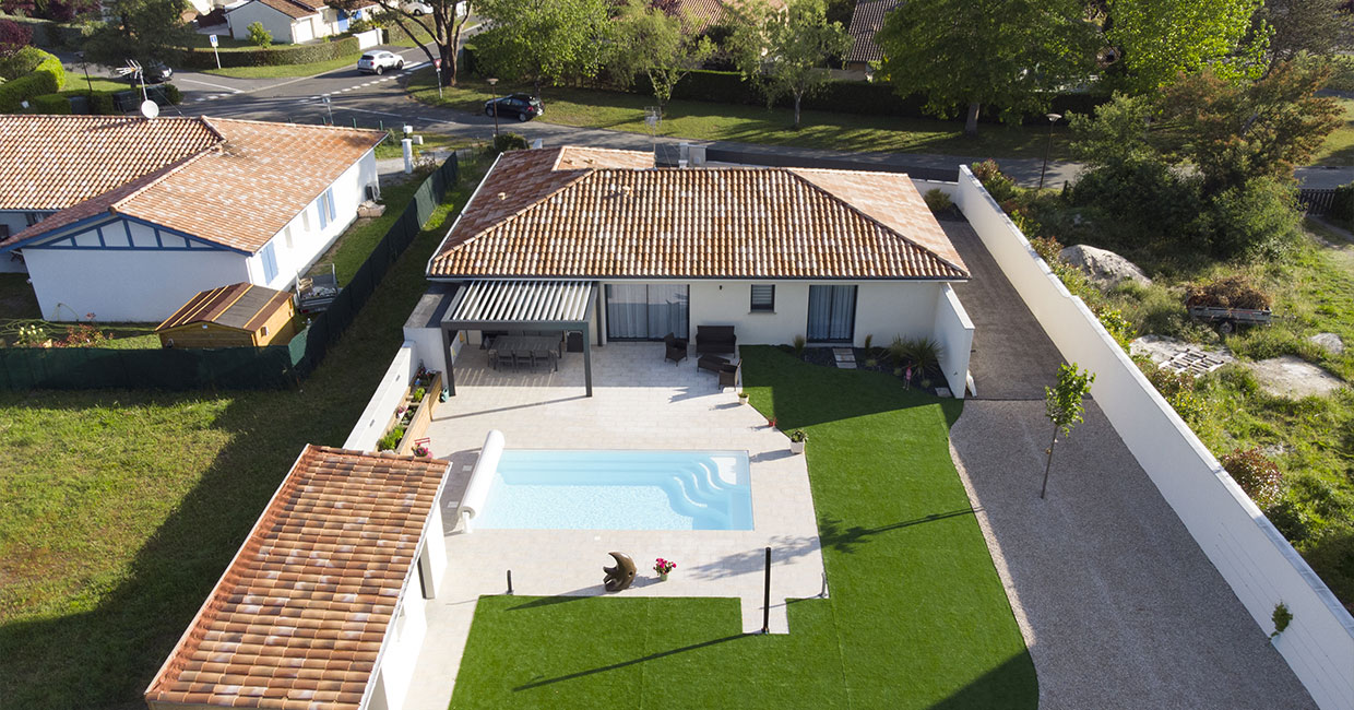 vue du ciel d'une maison contemporaine avec une architecture en L et une piscine