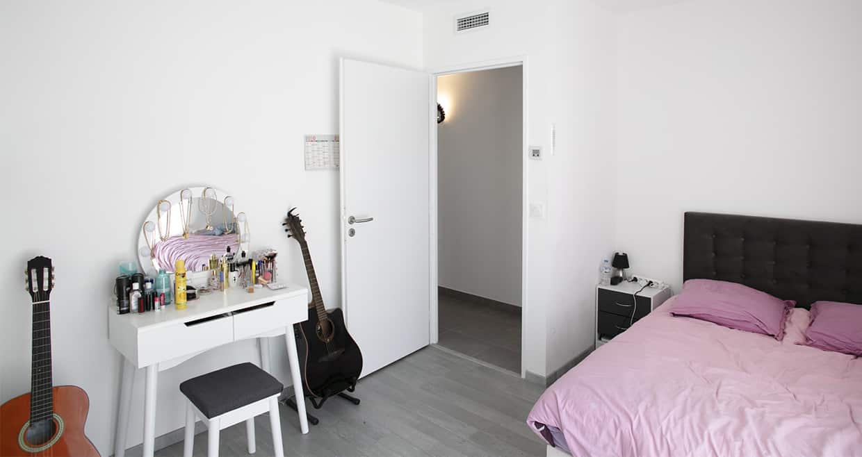 Chambre d'adolescent avec un grand lit, une coiffeuse et une guitare