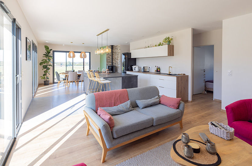 Salon-séjour d'une maison lumineuse avec canapé et cuisine ouverte
