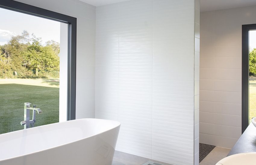 Salle de bain avec baignoire hors sol et ouverture vers le jardin