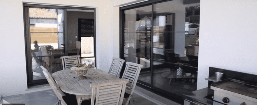 Terrasse extérieure couverte proche de grandes baies vitrées et avec table pour manger