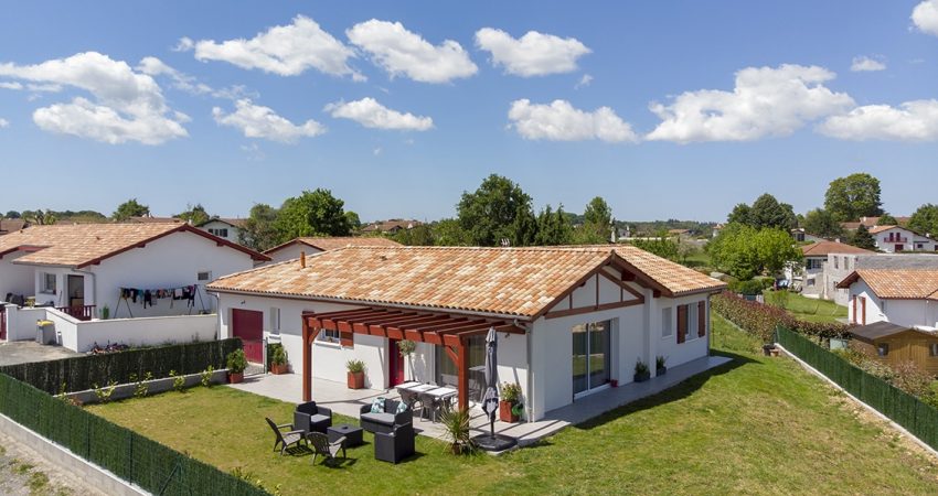 Vue aérienne d'une maison en L avec terrasse et jardin