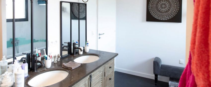 Une double vasque dans une salle de bain au style industriel avec miroirs en métal