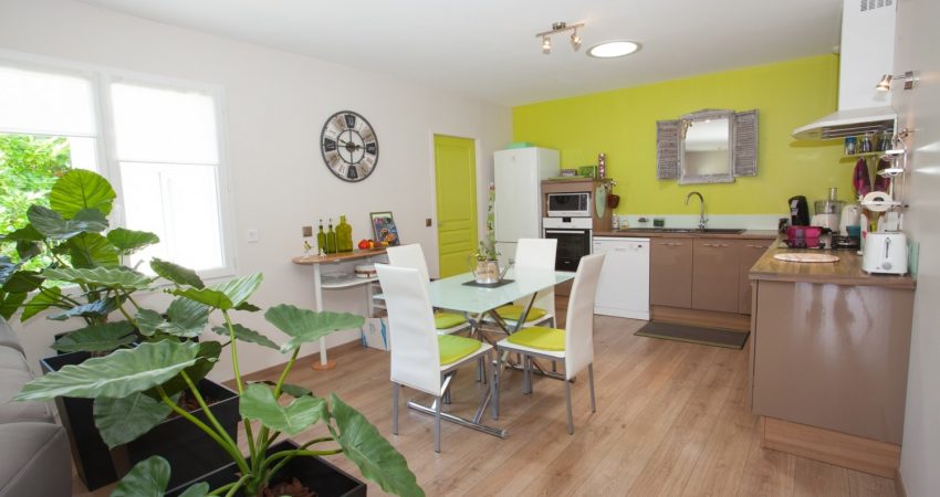 Entrée d'une maison sur une cuisine colorée avec horloge murale